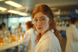 © EJManzaneque - A young red-haired woman in a lab coat and goggles stands in front of a group of scientists.
