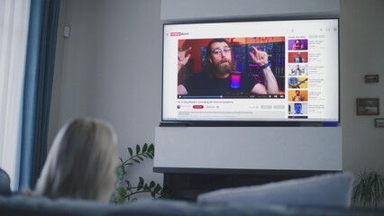 Poster - adult woman watches educational video of blogger about stock trading or investment on the big tv scr