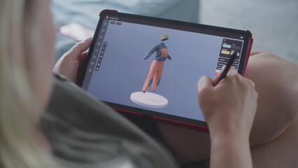 Poster - Caucasian woman creates model in 3D modeling design app using tablet computer and digital pen. Adult woman makes freelance working project lying on sofa at home. Lifestyle and remote work. Close Up.