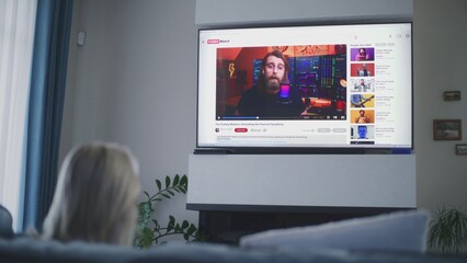 Poster - adult woman watches educational video of blogger about stock trading or investment on the big tv scr