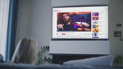 Poster - adult woman watches educational video of blogger about stock trading or investment on the big tv scr