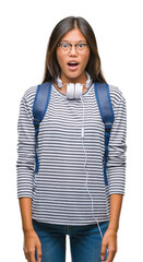 Canvas Print - Young asian student woman wearing headphones and backpack over isolated background afraid and shocked with surprise expression, fear and excited face.