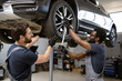 © sofiko14 - Mechanics performing tire maintenance on car in auto repair shop. Teamwork and cooperation in automotive service. Professional technicians using tools for car repair and maintenance.