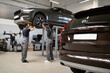 © sofiko14 - Professional mechanics repairing car in modern auto repair shop. Two technicians inspecting vehicle on lift. Automotive service, maintenance and teamwork in clean workshop environment.