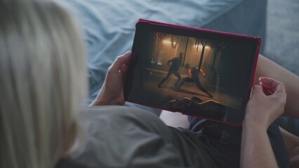 Poster - close up of woman watching action movie using tablet computer while lying on sofa. caucasian woman r