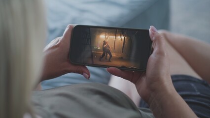 Poster - caucasian woman watches action movie using smartphone while lying on sofa. mobile phone screen with 
