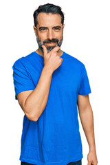 Sticker - Middle aged man with beard wearing casual blue t shirt looking confident at the camera smiling with crossed arms and hand raised on chin. thinking positive.