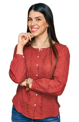 Wall Mural - Young hispanic woman wearing casual clothes looking confident at the camera with smile with crossed arms and hand raised on chin. thinking positive.