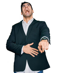 Wall Mural - Handsome hispanic man wearing business clothes laughing at you, pointing finger to the camera with hand over body, shame expression