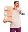 © Krakenimages.com - Young handsome man holding delivery package smiling happy doing ok sign with hand on eye looking through fingers