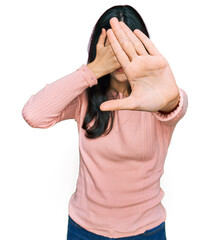 Wall Mural - Young hispanic woman wearing casual clothes covering eyes with hands and doing stop gesture with sad and fear expression. embarrassed and negative concept.