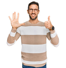 Canvas Print - Handsome man with beard wearing casual clothes and glasses showing and pointing up with fingers number six while smiling confident and happy.