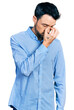 © Krakenimages.com - Hispanic man with beard wearing casual business shirt tired rubbing nose and eyes feeling fatigue and headache. stress and frustration concept.