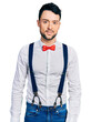 © Krakenimages.com - Hispanic man with beard wearing hipster look with bow tie and suspenders relaxed with serious expression on face. simple and natural looking at the camera.