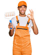 © Krakenimages.com - Young handsome african american man wearing cap and painter clothes holding painting roll doing ok sign with fingers, smiling friendly gesturing excellent symbol
