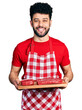 © Krakenimages.com - Young arab man with beard holding board with raw meat smiling and laughing hard out loud because funny crazy joke.