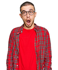 Wall Mural - Hispanic young man wearing casual clothes afraid and shocked with surprise and amazed expression, fear and excited face.