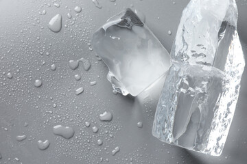 Poster - Pieces of clear ice and water drops on light grey table, top view. Space for text