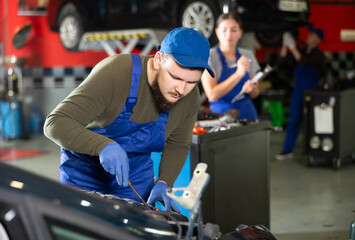 Wall Mural - Professional mechanic man in uniform repairing car in auto repair shop garage