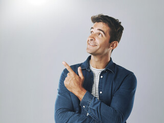 Poster - Man, studio and pointing at mockup for choice, opinion and idea on gray background. Male designer, decision and hand gesture for product with smile, guide and information for industry on copy space