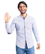 © Krakenimages.com - Handsome hispanic man wearing business shirt and glasses waiving saying hello happy and smiling, friendly welcome gesture