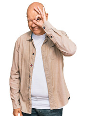 Wall Mural - Middle age bald man wearing casual clothes doing ok gesture with hand smiling, eye looking through fingers with happy face.