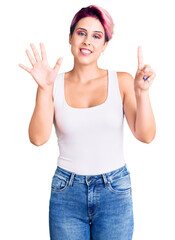 Wall Mural - Young beautiful woman with pink hair wearing casual clothes showing and pointing up with fingers number six while smiling confident and happy.