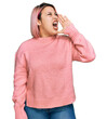 © Krakenimages.com - Hispanic woman with pink hair wearing casual winter sweater shouting and screaming loud to side with hand on mouth. communication concept.