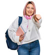 © Krakenimages.com - Hispanic woman with pink hair wearing student backpack and headphones pointing to you and the camera with fingers, smiling positive and cheerful