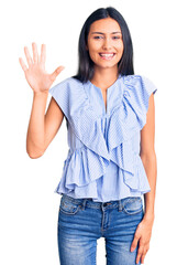 Sticker - Young beautiful latin girl wearing casual clothes showing and pointing up with fingers number five while smiling confident and happy.