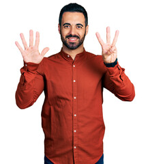 Wall Mural - Young hispanic man with beard wearing casual shirt showing and pointing up with fingers number eight while smiling confident and happy.