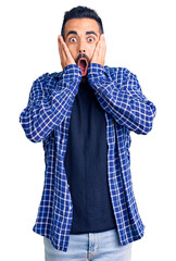 Poster - Young hispanic man wearing casual clothes afraid and shocked, surprise and amazed expression with hands on face