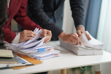 Two accountants working with piles of documents in office business finance and accounting concepts Businessman picks up overloaded documents Try to organize and categorize documents in your office.