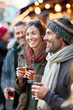 © Dar1930 - A group of people standing at a Christmas market and drinking mulled wine, Christmas party. AI generative.
