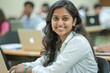 © LimeSky - Portrait of a smart young Indian woman student in a white shirt and green tracker happily studying on her laptop in a university classroom