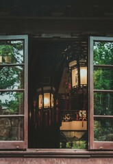 A view through a wooden window frame of a dimly lit room with two traditional Chinese lanterns hanging from the ceiling.