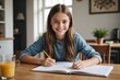 © ThomasLENNE - Portrait happy teenage girl doing homework at dining table