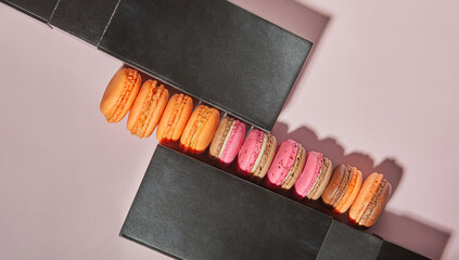 Wall Mural - Colorful macarons of different flavors between boxes on a pink background with shadow