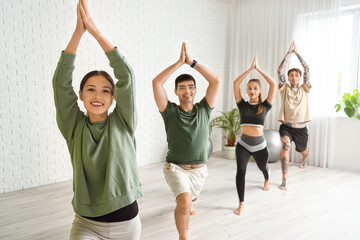 Canvas Print - Group of sporty young people practicing yoga in gym