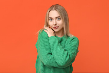 Wall Mural - Young woman hugging herself on orange background