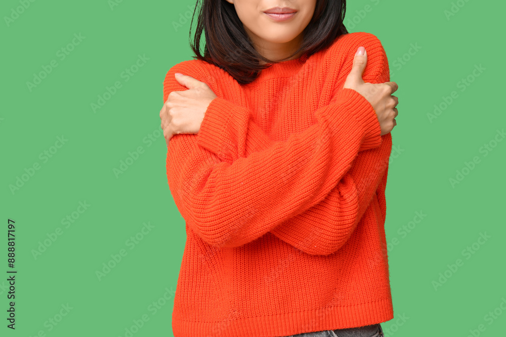 Young Asian woman hugging herself on green background, closeup
