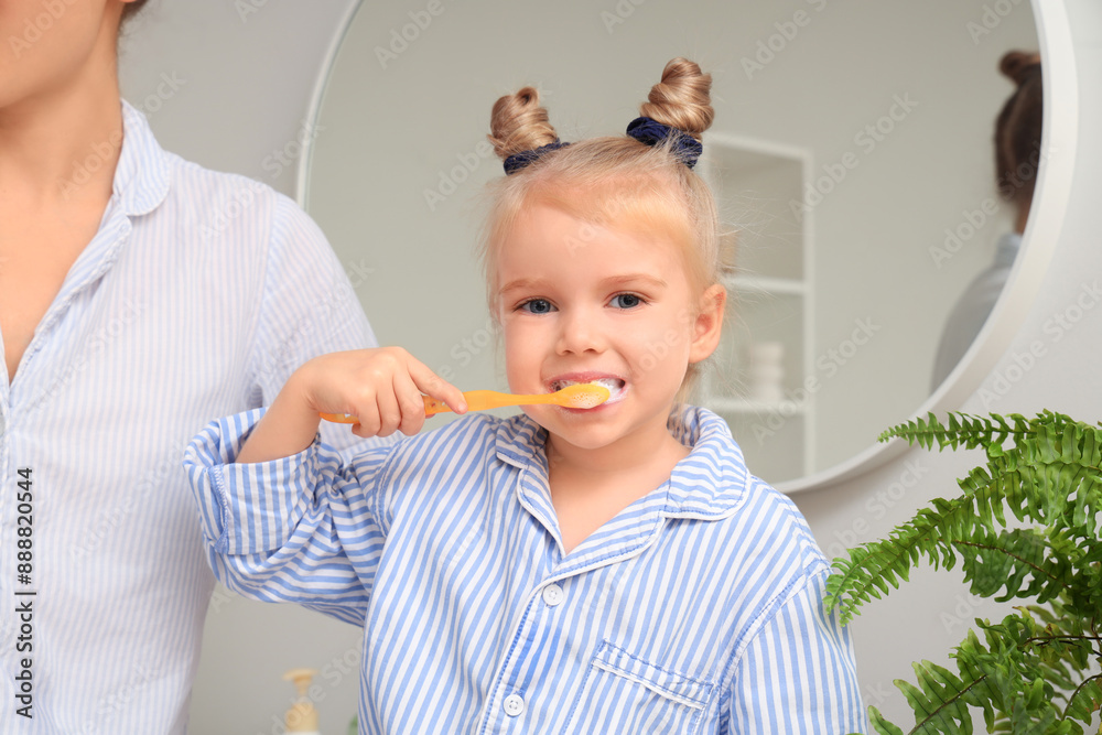 Mother and her little daughter brushing teeth in bathroom