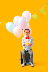 Poster - Cute little boy with Birthday cake and balloons sitting on yellow background