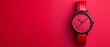 © Mikus - A red watch with a black face against a red background The clock face casts a shadow