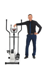 Poster - Mature businessman with exercising bike on white background