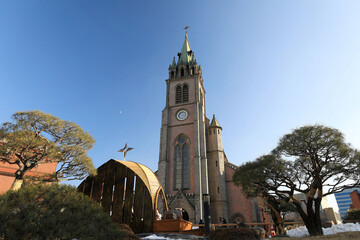 Myeong-dong, Jung-gu, Seoul, South Korea - December 30, 2022: Low angle and afternoon view of pine trees and building of Myeongdong Cathedral in winter
