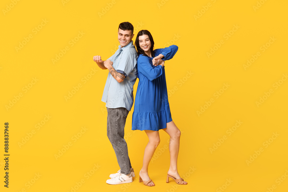 Beautiful young couple dancing on yellow background