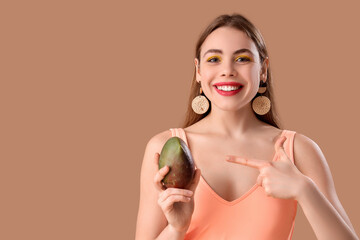 Poster - Beautiful young woman pointing at sweet mango fruit on brown background