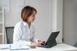 © crizzystudio - Young Asian businesswoman sitting at work using laptop and calculator document to calculate online finance, tax, accounting, statistics and analytical research concepts.