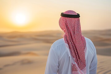 Wall Mural - saudi gulf arab man wearing a traditional white thobe and red shemagh, standing in the desert during